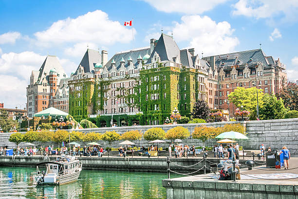 The iconic Fairmont Empress Hotel in Victoria, BC, surrounded by waterfront and tourists on a sunny day.